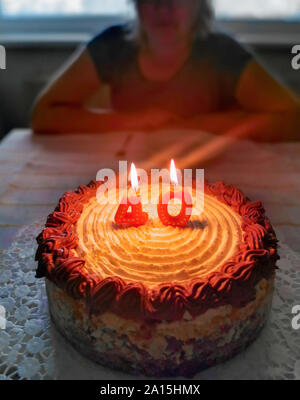 Torta per il quarantesimo compleanno con candele con donna bionda in background Foto Stock