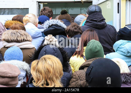 La folla di persone vicino all'entrata dello store durante la vendita. Shoppers immettere il mall sul Venerdì nero. Inverno, vendita autunnale, sconti. Gente occupata di stand in un Foto Stock