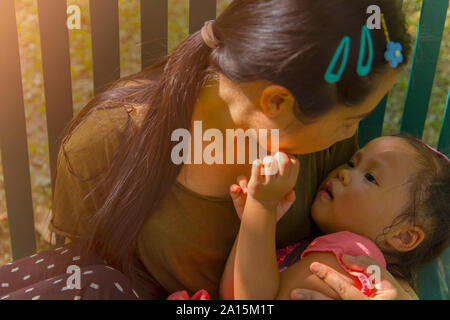 Giovane madre abbraccia e calmante di un pianto piccola figlia, Asian madre cercando di comfort e di calmare il suo pianto bambino immagine ad alta risoluzione galler Foto Stock