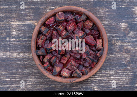 Cotta barbabietola rossa con miele sul tavolo di legno, vicino. Vaso in ceramica con viola le fette di barbabietole sfondo, vista dall'alto Foto Stock