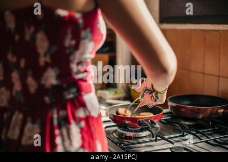Close-up della donna per la cottura in cucina utilizzando una padella Foto Stock