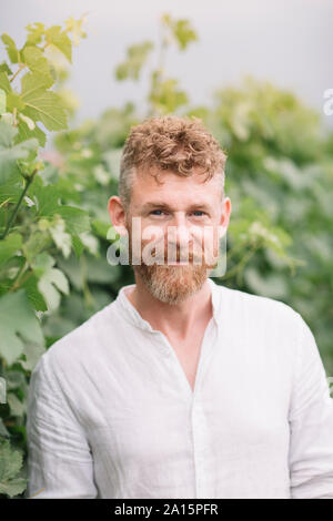 Ritratto di uomo barbuto davanti a grapevine Foto Stock