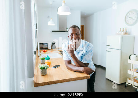 Ritratto di giovane sorridente uomo in cucina a casa Foto Stock