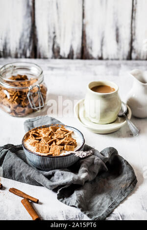 Close-up di fresco cotto in casa cannella cereali con aggiunta di yogurt in un recipiente sul tavolo Foto Stock
