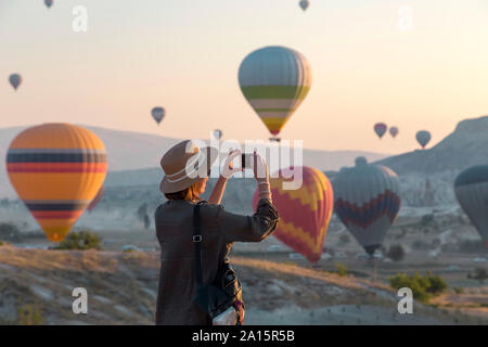 Giovane donna e aria calda ballons, Goreme, Cappadocia, Turchia Foto Stock