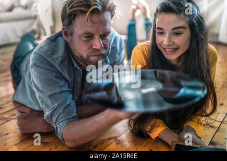 Giovane sdraiato sul pavimento a casa con un record Foto Stock