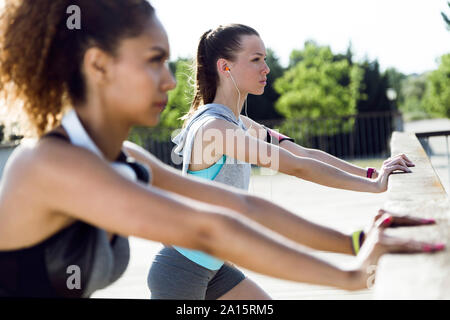 Sportivo di due giovani donne stiramento sulla ringhiera del ponte Foto Stock