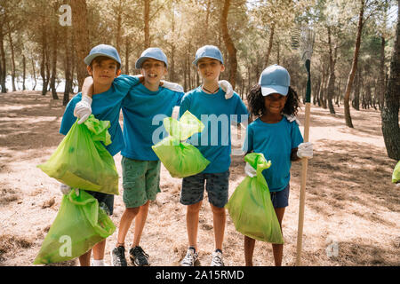 Ritratto di gruppo di volontariato bambini raccogliere rifiuti in un parco Foto Stock