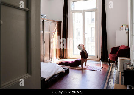 Bruna giovane donna a praticare yoga in dormitorio studenti Foto Stock