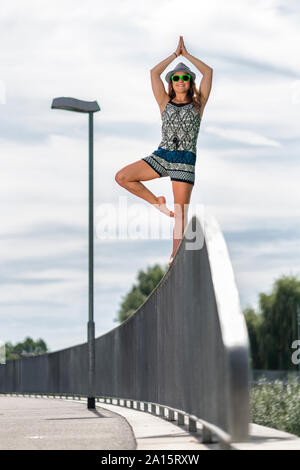 Sorridente giovane donna in equilibrio su una ringhiera a ponte Foto Stock