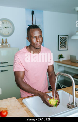 Giovane uomo di lattuga di lavaggio in cucina Foto Stock