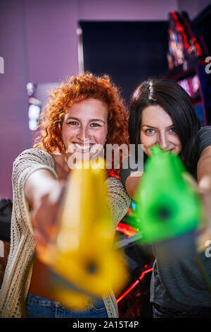 Happy amici a suonare e a sparare con pistole in un divertimento arcade Foto Stock