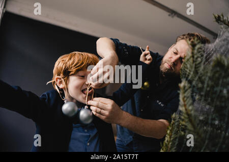 Padre decorare il suo figlio al tempo di Natale Foto Stock