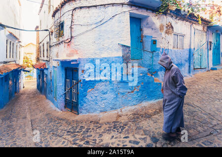 Uomo che cammina nella vecchia città di Chefchaouen con i famosi edifici di colore blu, Chefchaouen, Marocco Foto Stock