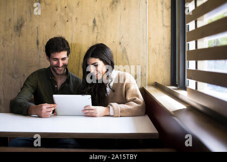 Ridendo giovane utilizzando digitale compressa in un cafe Foto Stock