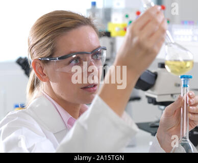 Scienziato esaminando una formula chimica in un pallone da laboratorio Foto Stock