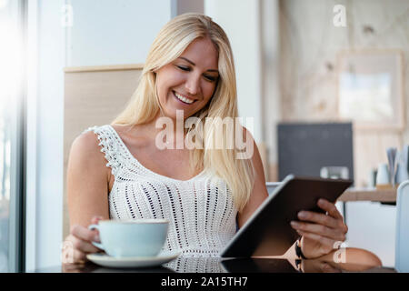 Ritratto di sorridere donna bionda in un cafe con tavoletta digitale Foto Stock