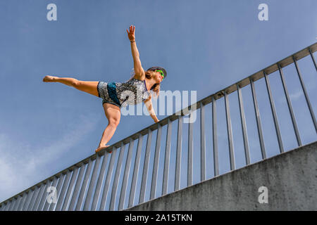 Sorridente giovane donna in equilibrio su una ringhiera a ponte Foto Stock