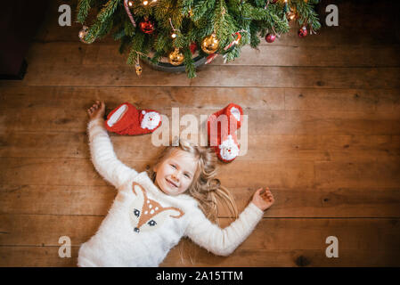 Sorridente ragazza distesa sotto l albero di Natale Foto Stock