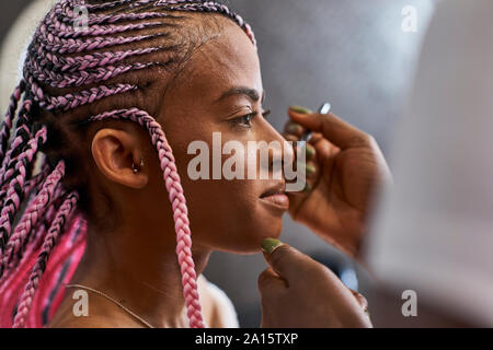 Visagiste applicare il trucco sul giovane volto di donna Foto Stock