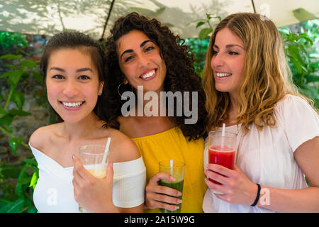 Ritratto di felice tre giovani donne azienda drink salutari Foto Stock