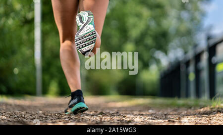 Piedi di una giovane donna jogging su un sentiero di truciolo Foto Stock