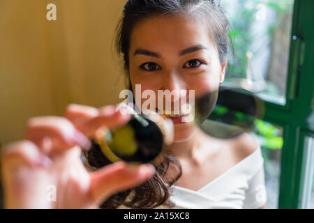 Ritratto di sorridente giovane donna azienda occhiali da sole Foto Stock