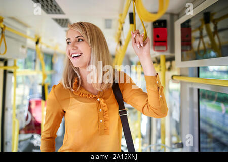 Felice giovane donna con lo smartphone in un tram Foto Stock