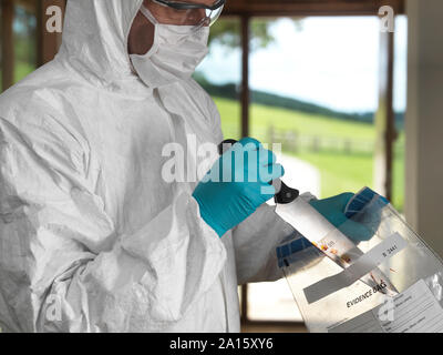 Lo scienziato forense in sacchi un coltello preso da un violento della scena del crimine Foto Stock