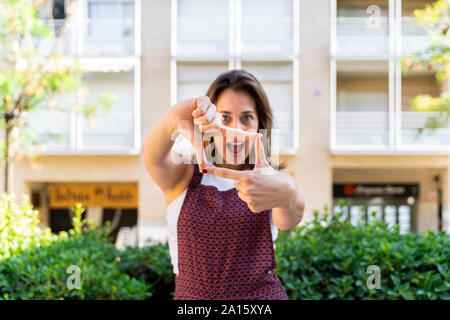 Ritratto di giovane donna che fa un segno a mano per selfie Foto Stock