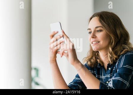 Giovane donna utilizza lo smartphone, sorridente Foto Stock