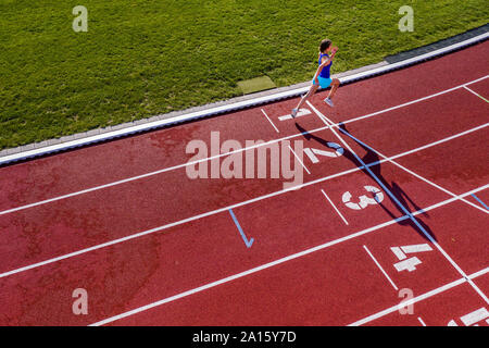 Vista aerea di esecuzione di un giovane atleta femminile su una pista di tartan Attraversamento linea di finitura Foto Stock