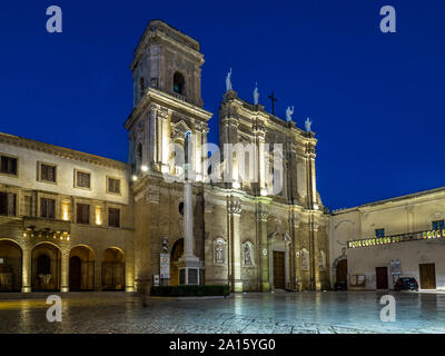 La facciata della cattedrale illuminata a Brindisi contro il cielo blu e chiaro di notte Foto Stock