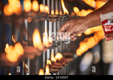 Illuminazione a mano candela nel tempio della Sacra Reliquia del Dente, Kandy, Sri Lanka Foto Stock