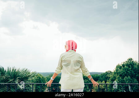 Senior donna con velo di colore rosa cercando di visualizzare Foto Stock