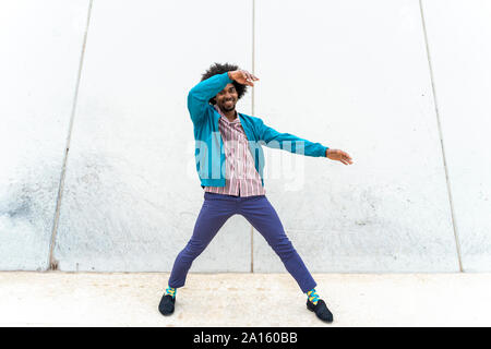 Giovane uomo parigamba dancing, muro bianco in background Foto Stock