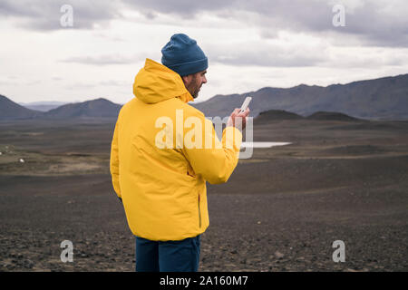 Uomo maturo utilizza lo smartphone nelle lingue islandese highlands Foto Stock