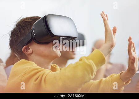 Little Boy giocando con gli occhiali VR, sittiing sul lettino con la sua famiglia Foto Stock