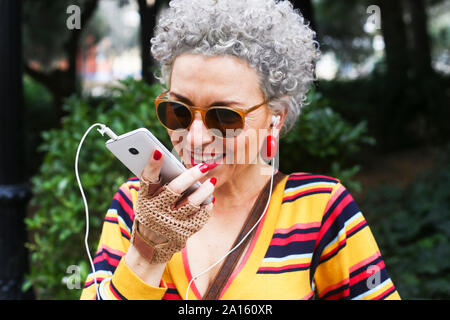 Ritratto di trafitto donna matura utilizza lo smartphone all'aperto Foto Stock