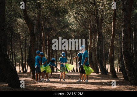 Gruppo di volontariato bambini raccogliere rifiuti in un parco Foto Stock