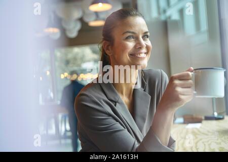 Imprenditrice sorridente in un bar a bere caffè Foto Stock