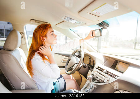 Business donna in un auto controllo del suo sguardo nello specchietto retrovisore Foto Stock