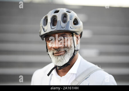 Ritratto di sorridente imprenditore maturo con barba grigia che indossa il ciclismo casco e occhiali di protezione Foto Stock