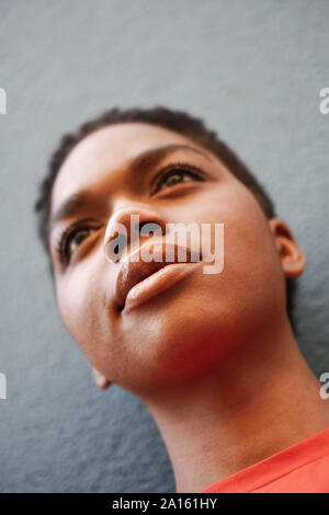Ritratto di giovane donna di fronte a muro grigio, close-up Foto Stock