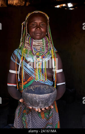 Ritratto di un tradizionale Muhila woman standing in casa sua holding pot, Congolo, Angola Foto Stock