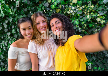 Ritratto di tre sorridenti giovani donne prendendo un selfie Foto Stock