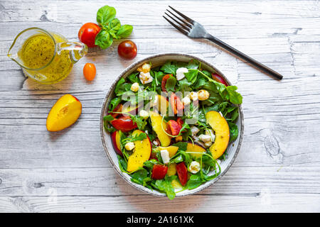 Direttamente sopra vista di insalata fresca in vasca dalla brocca e la forcella sulla tavola Foto Stock