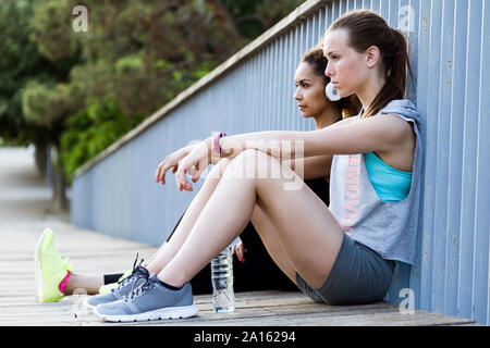 Sportivo di due giovani donne relax su un ponte dopo allenamento Foto Stock