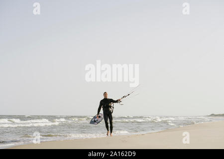 Kiteboarder camminando con il suo kite in spiaggia Foto Stock