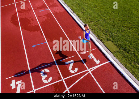 Vista aerea di esecuzione di un giovane atleta femminile su una pista di tartan Attraversamento linea di finitura Foto Stock